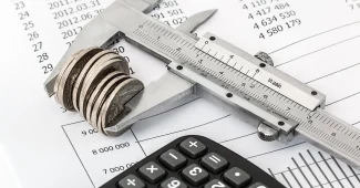 Bureau avec factures, relevés bancaires et écran affichant des tableaux de bord financiers