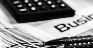 Mains anonymes sur un contrat et une calculatrice près d'une fenêtre en pleine journée