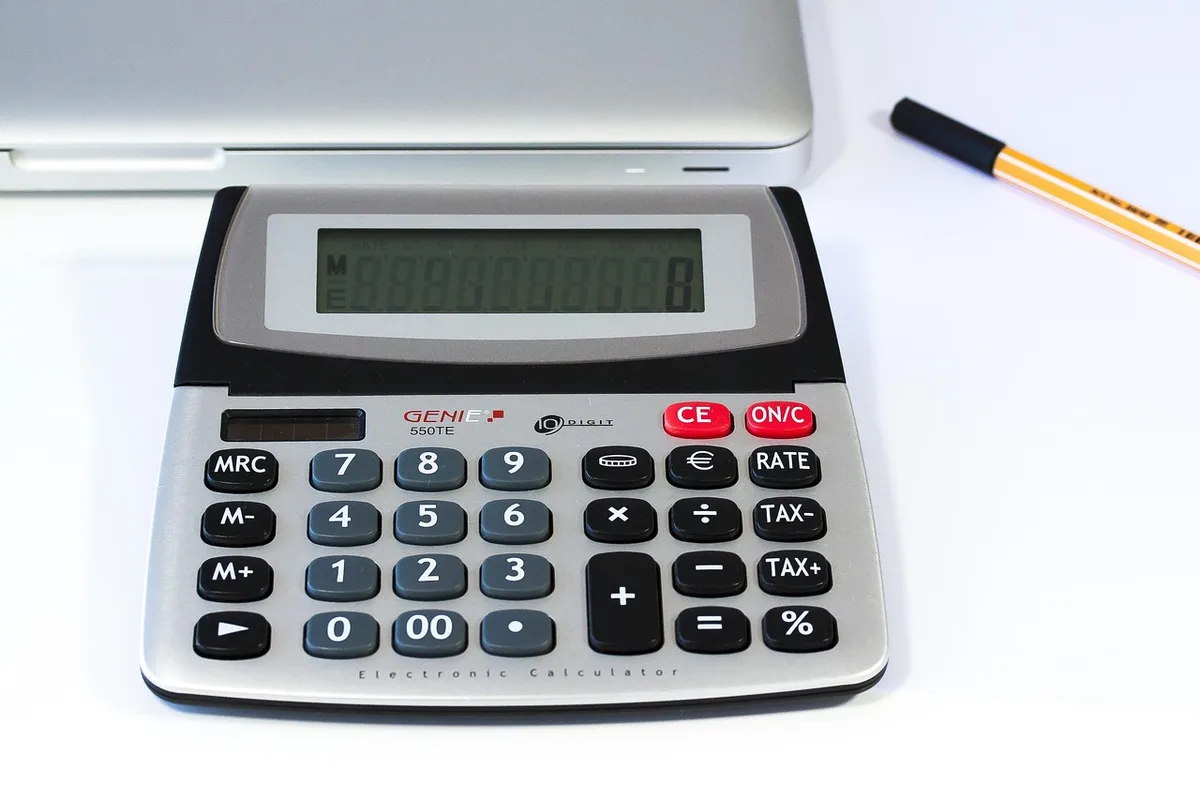 Étudiant vérifiant son budget sur ordinateur avec calculatrice