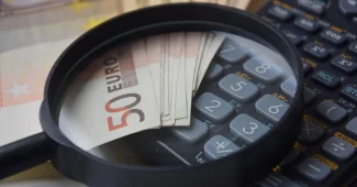 Bureau en plein jour avec bulletin de salaire, calculatrice et ordinateur portable