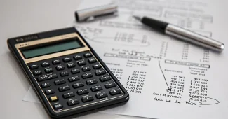 Bureau lumineux avec contrat ouvert, calculatrice et mains montrant un graphique