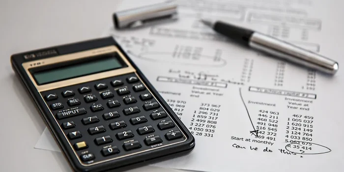 Bureau lumineux avec contrat ouvert, calculatrice et mains montrant un graphique