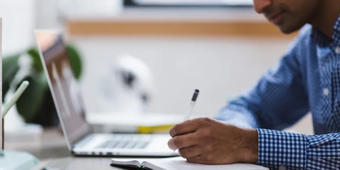 Personne anonyme remplissant un formulaire bancaire sur un bureau en plein jour