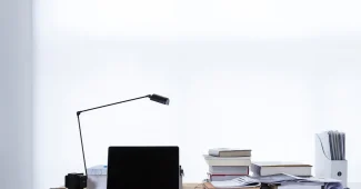 Mains tenant des documents financiers et une calculatrice sur un bureau près d'une fenêtre en journée