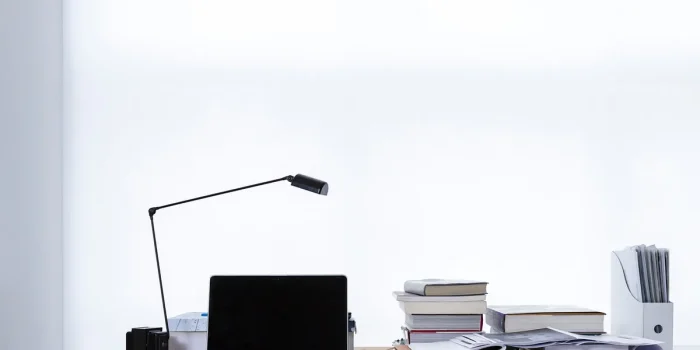 Mains tenant des documents financiers et une calculatrice sur un bureau près d'une fenêtre en journée
