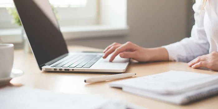 Bureau en journée avec cahier de comptes, ordinateur portable et mains sur une checklist