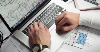 Bureau lumineux avec ordinateur portable, mains anonymes et factures sur une table