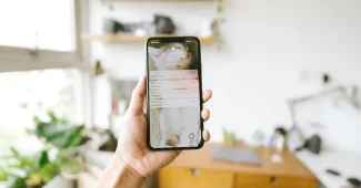 Smartphone posé sur une table près d'une fenêtre, écran d'applications flou en arrière-plan