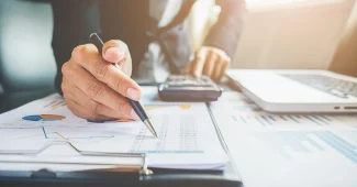 Bureau lumineux avec documents de PER et mains tenant une fiche de paie