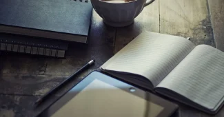 Mains sur un contrat PER avec tablette montrant graphiques financiers sur un bureau en plein jour