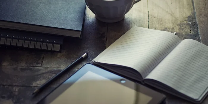 Mains sur un contrat PER avec tablette montrant graphiques financiers sur un bureau en plein jour