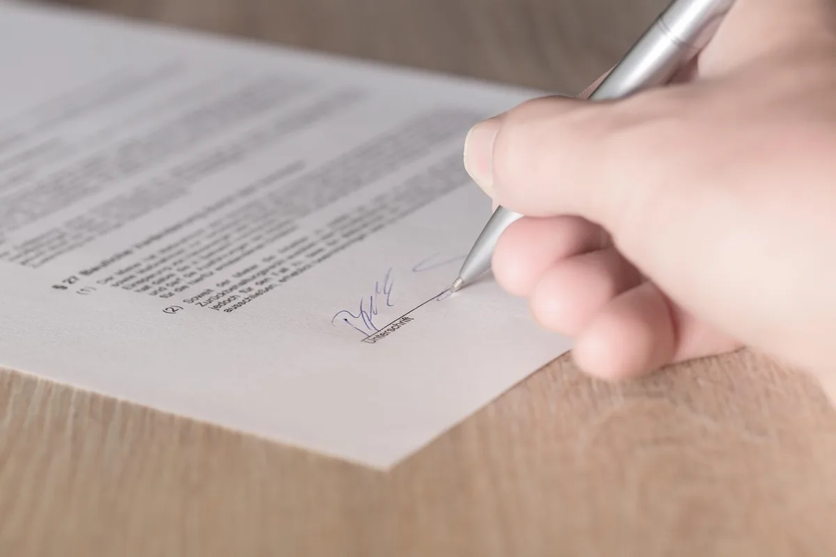 Contrat et documents juridiques posés sur un bureau en lumière du jour