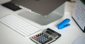 Fiche de paie et calculatrice sur un bureau baigné de lumière du jour