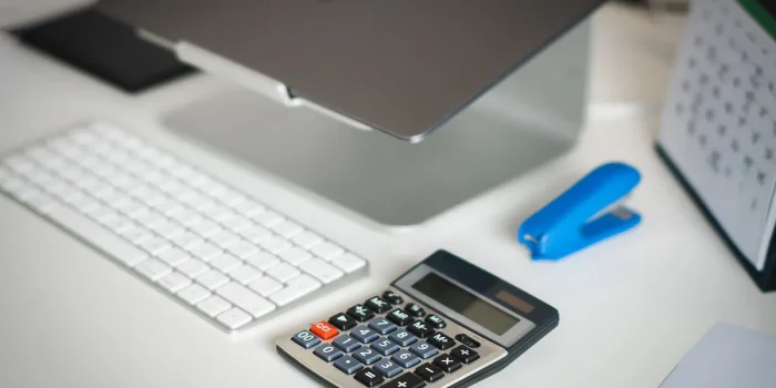 Fiche de paie et calculatrice sur un bureau baigné de lumière du jour