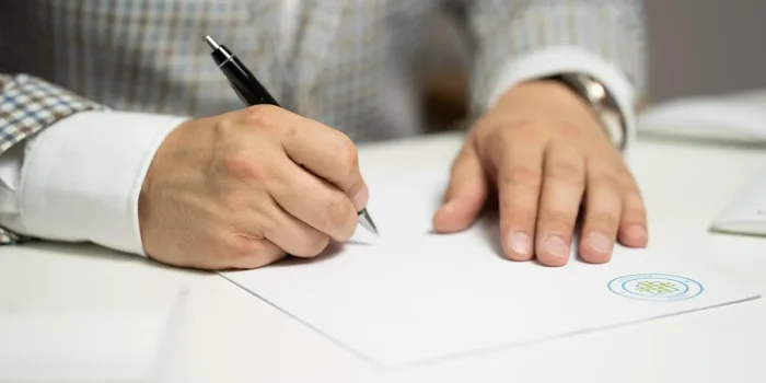 Bureau en journée avec bulletin de paie, calculatrice et mains indiquant une ligne