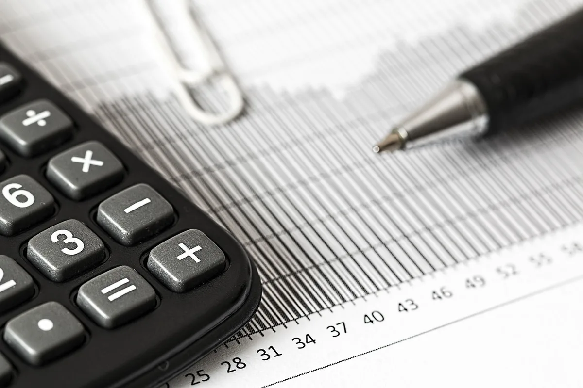Personne triant des feuilles de budget et un calculateur sur une table